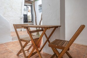 Ein Holztisch mit Stühlen vor einer weißen Wand mit Fliesenboden.