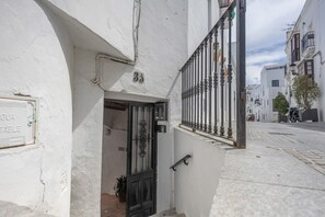 Un vicolo stretto con edifici bianchi, un cancello nero e una ringhiera metallica.