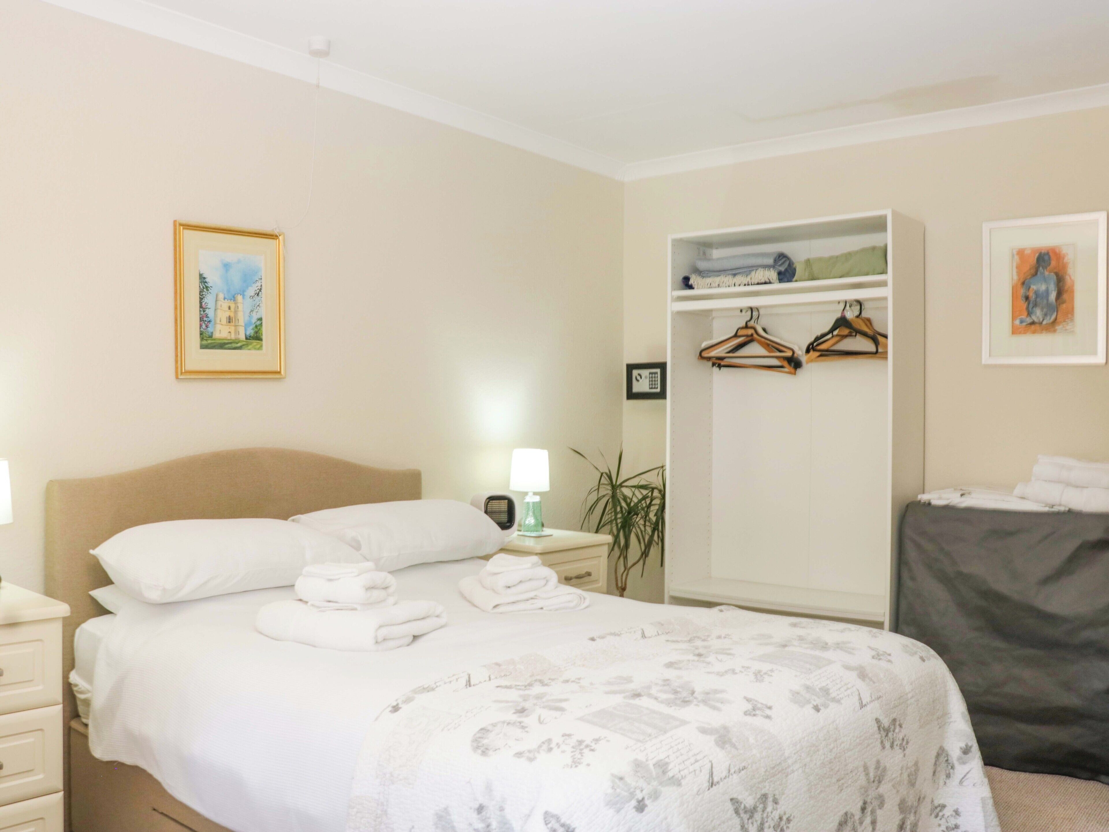 Un dormitorio con cama, mesitas de noche, un armario y un cuadro en la pared.