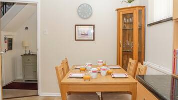 A dining area with a wooden table, chairs, a clock, and a cabinet with glass doors.