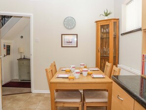Un comedor con una mesa de madera, sillas, un reloj y un aparador con puertas de vidrio.