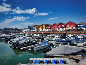 A marina with boats docked, a row of colorful houses, and a clear blue sky. - Halsdon Avenue (Exmouth)