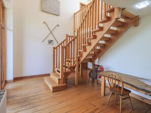 A wooden staircase in a room with a wooden floor, a small table, and a chair.