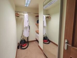 A narrow hallway with a mirror, a vacuum cleaner, a towel rack, and a wooden door. - Shepherd's Barn (Lancaster)