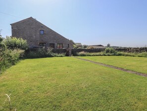 A stone building with a sloped roof, a grassy yard, and a stone wall. - Shepherd's Barn (Lancaster)