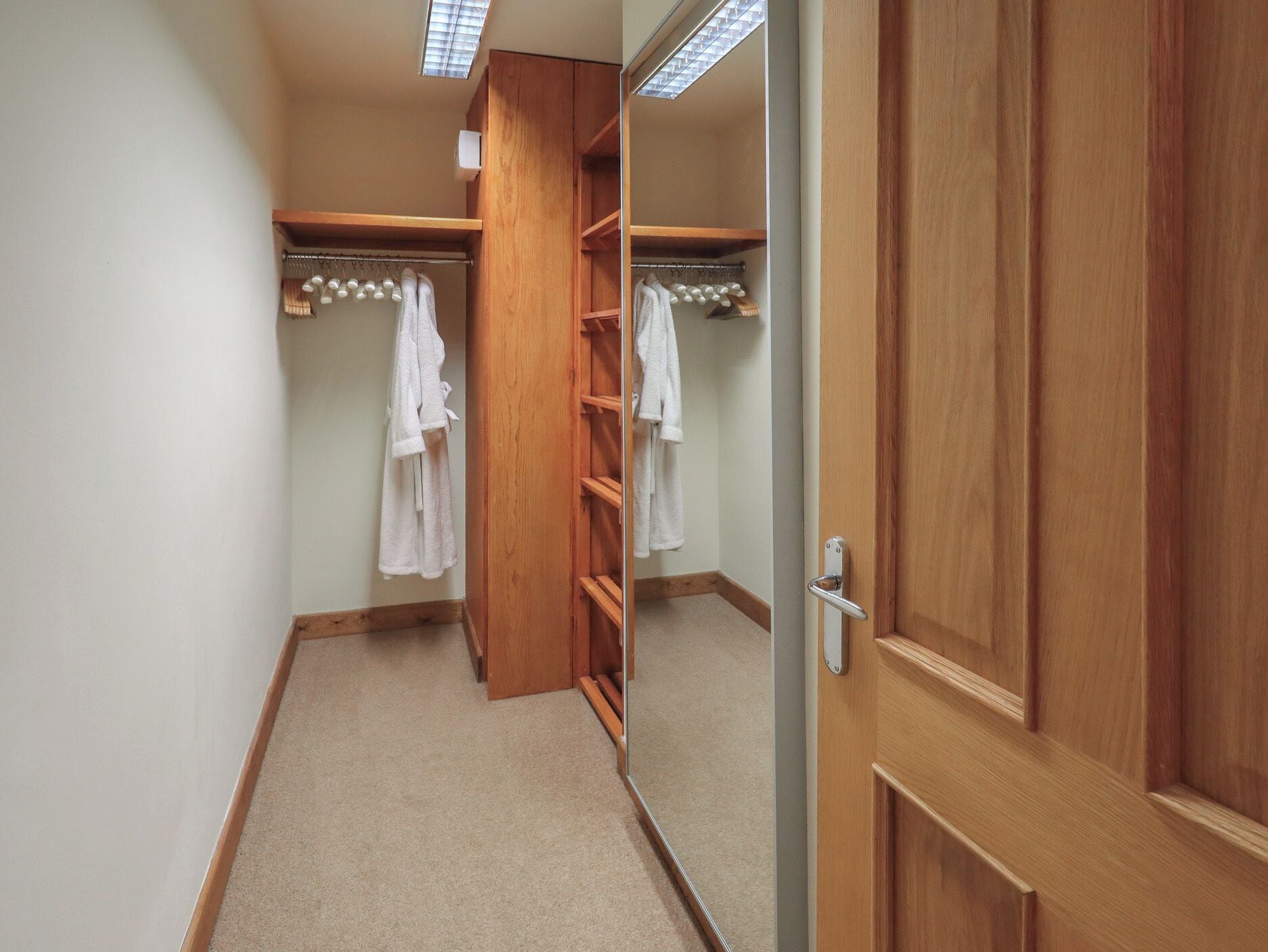 Un armario vestidor con estantes de madera y espacio para colgar ropa.