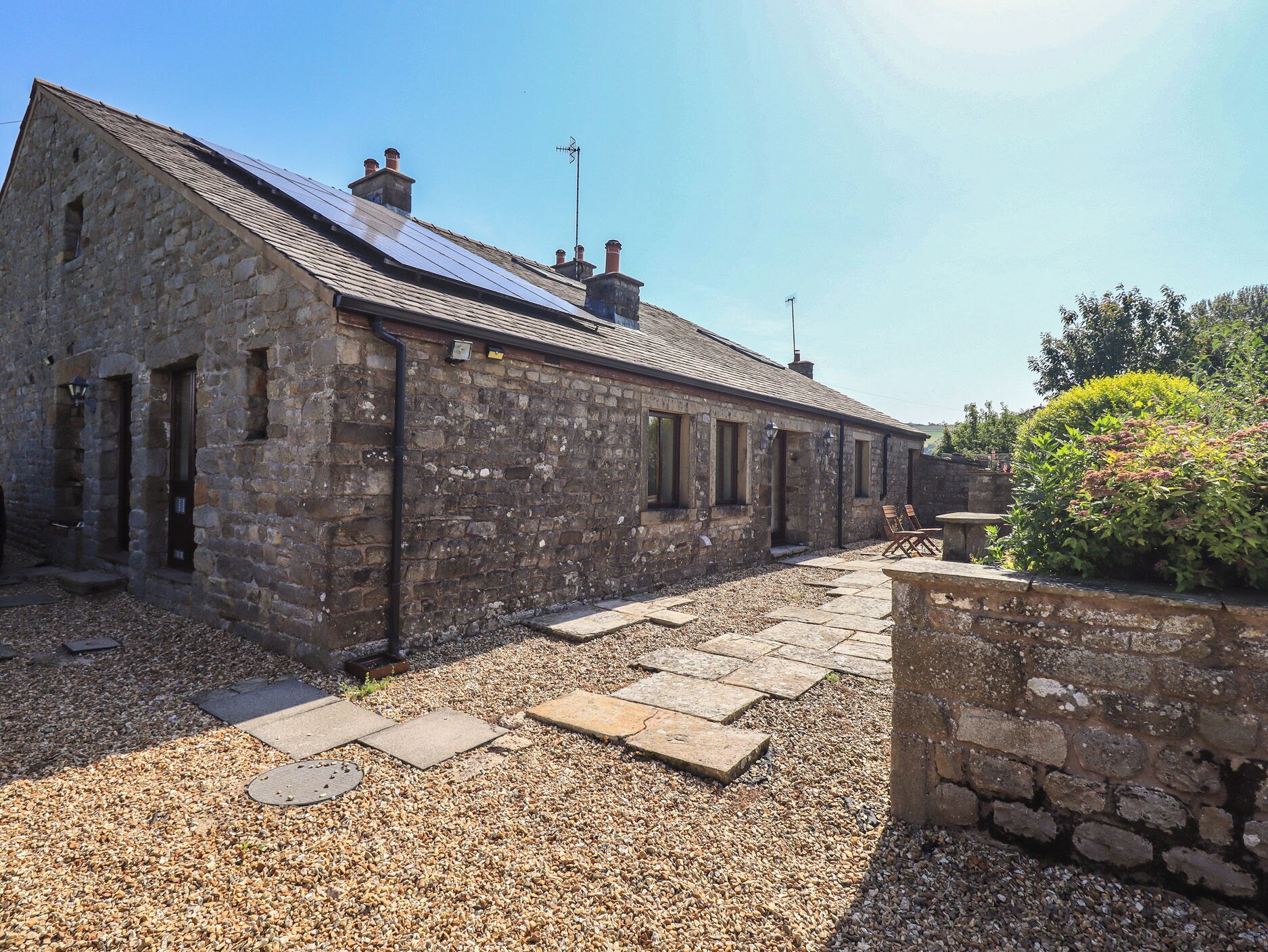 A stone building with a sloped roof and solar panels.