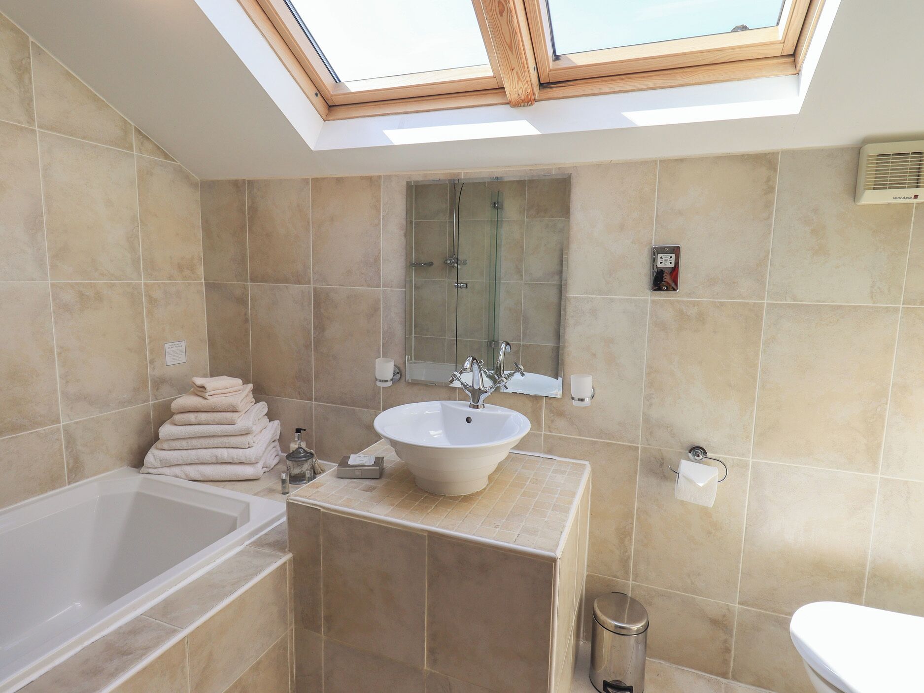 Ein modernes Badezimmer mit Oberlicht, Badewanne, Waschbecken und Toilette.
