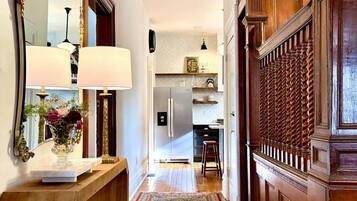 The entry hall on a bright afternoon, high ceilings opening all the way back to the kitchen