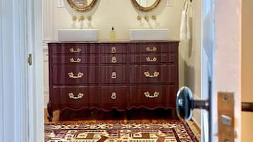 The Manor Suite's private bath — double sinks on a plum-lacquered vanity, getting ready is an event