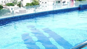 A swimming pool with clear blue water, a tiled edge, and a metal pool ladder. - Indigo Heights Hotel and Suites (Lahore)