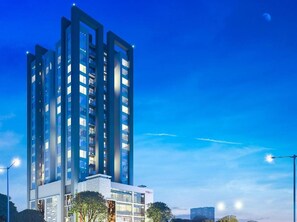 Un moderno edificio de gran altura con varios pisos, ventanas amplias y una fachada bien iluminada.