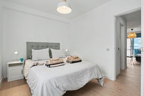 Ein Schlafzimmer mit einem Bett, Nachttischen, einer Lampe und Blick ins Freie.