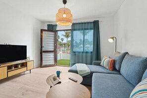 Un salon moderne doté d’un téléviseur à écran plat, d’un canapé, d’une table basse et d’un balcon offrant une vue agréable.