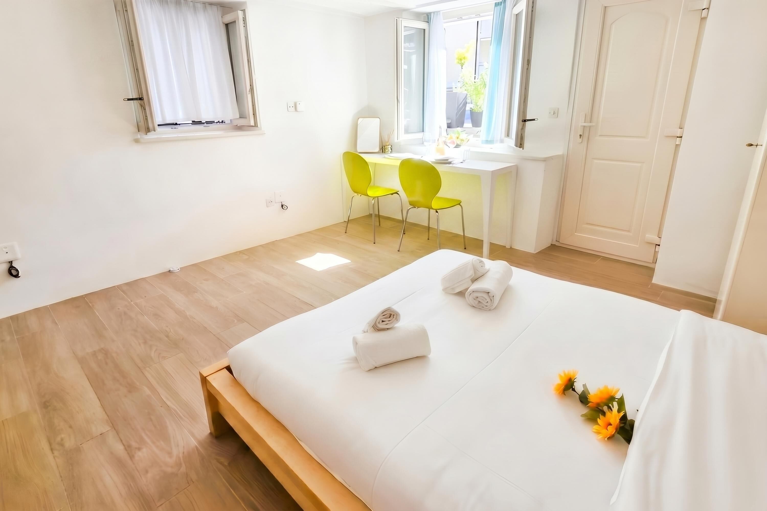 A hotel room with a bed, two chairs, a desk, and a window.