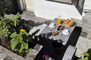 A stone table with a white tablecloth, a basket of croissants, a pitcher of orange juice, and a cup and saucer. - Casa Cecilia Ascona 500m From the Lake (Ascona)