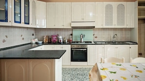 Una cocina con gabinetes blancos, estufa, horno y pileta.