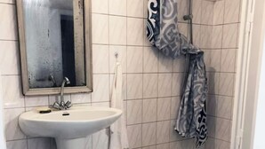 Et badeværelse med et håndvaskestel, et spejl, et håndklæde, en badeforhæng og et badekar.