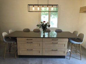 A dining area with a large rectangular table, six chairs, a vase with flowers, and a hanging light fixture. - Charming house that sleeps 10—luxury—with a pool and air conditioning (Barjols)
