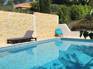 Ein Pool mit Steinmauern und zwei Liegestühlen.