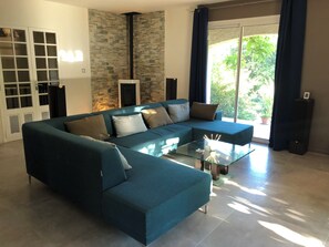 A modern living room with a sectional sofa, a glass coffee table, and a stone accent wall. - Charming house that sleeps 10—luxury—with a pool and air conditioning (Barjols)