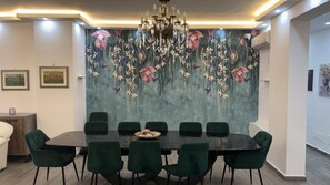 A dining area with a black table, green chairs, a chandelier, and a floral wall mural. - Vanila Dream's House (Palermo)