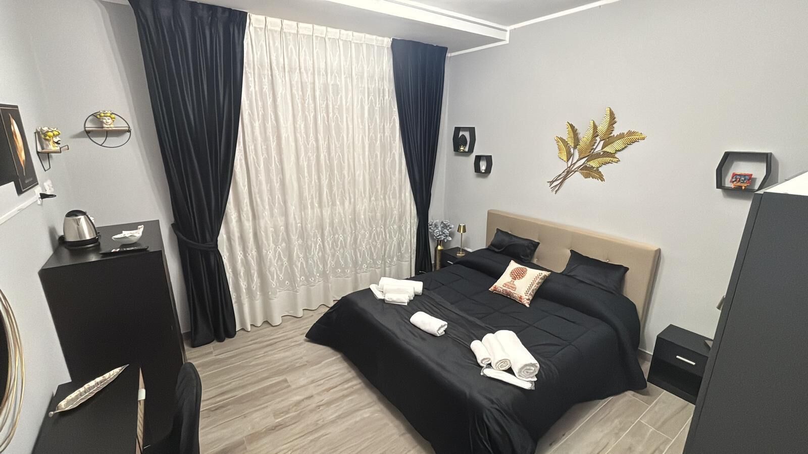 A modern hotel room with a bed, a desk, and a wardrobe.