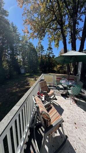 A deck with outdoor furniture, a table, and chairs, surrounded by trees and a clear sky. - Margaret s Retreat Cottage (York)
