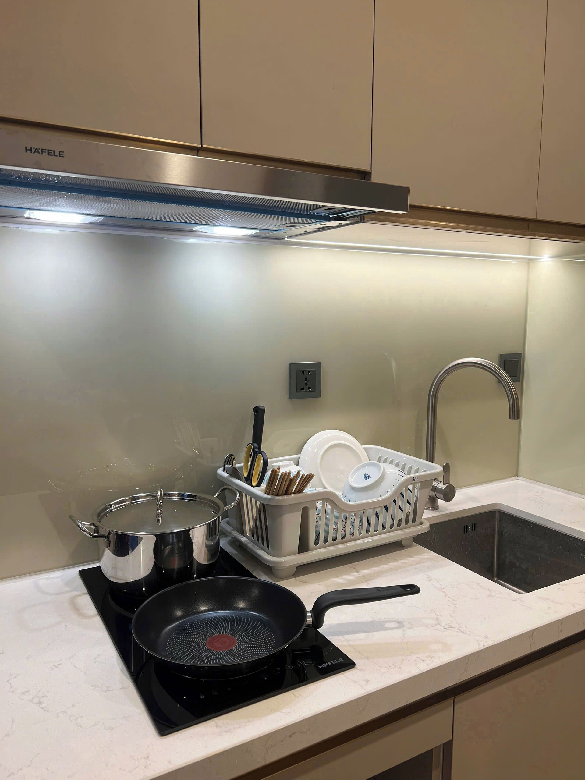 A kitchen with a stove, sink, and dish rack.