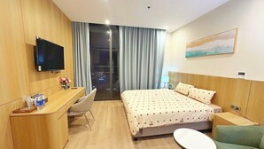A hotel room with a bed, desk, chair, and a TV. - Apartment in Icon 40 Ha Long   (Bai Chay)