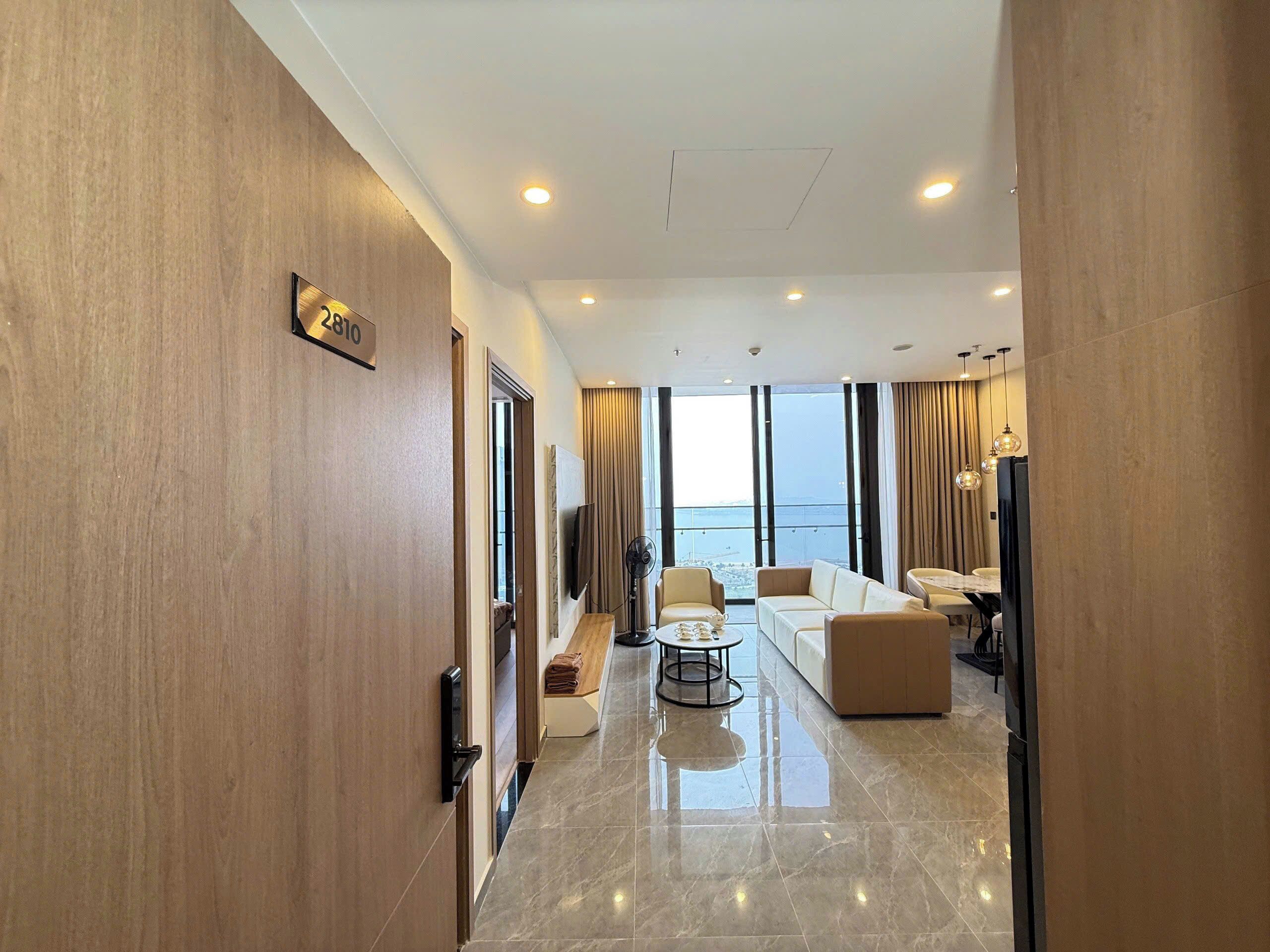 A modern hotel interior with a spacious living area, a large window offering a view, and a clean, polished floor.