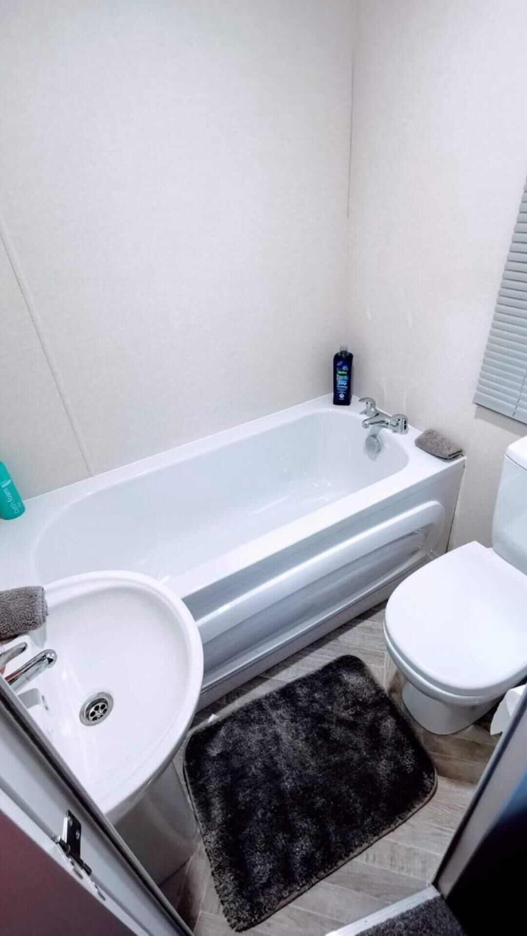Een badkamer met een bad, wastafel, toilet en een klein vloerkleed.