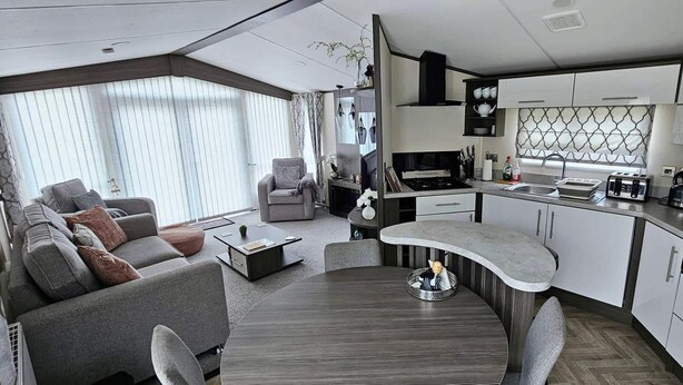 Interior moderno de autocaravana con sala de estar, cocina y comedor.