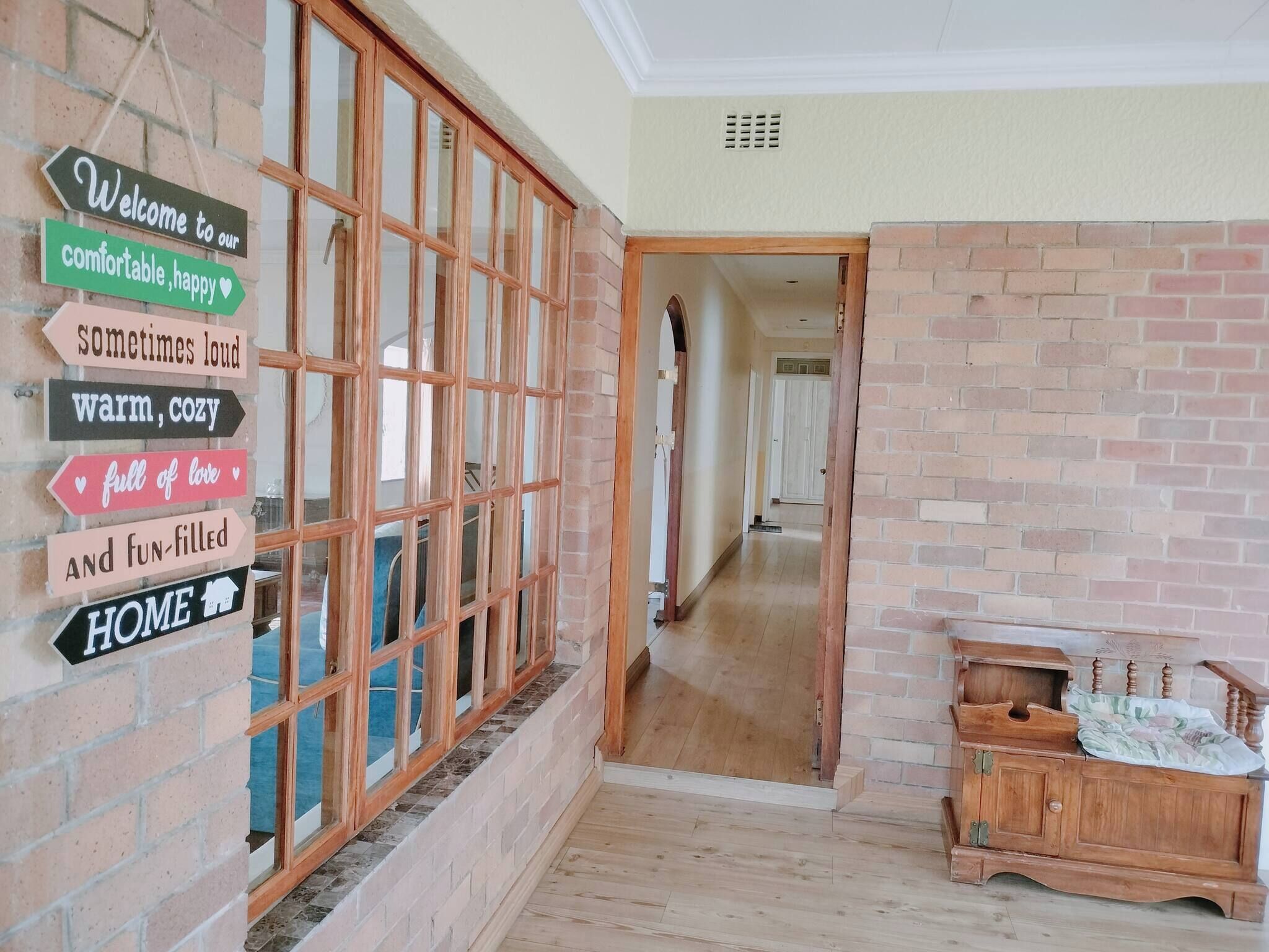 A hallway with a wooden bench, a brick wall, and a sign with directional arrows.