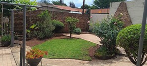 A well-maintained garden with a variety of plants and a brick wall. - Spacious Home, Families & Crews, Near Northcliff (Johannesburg)