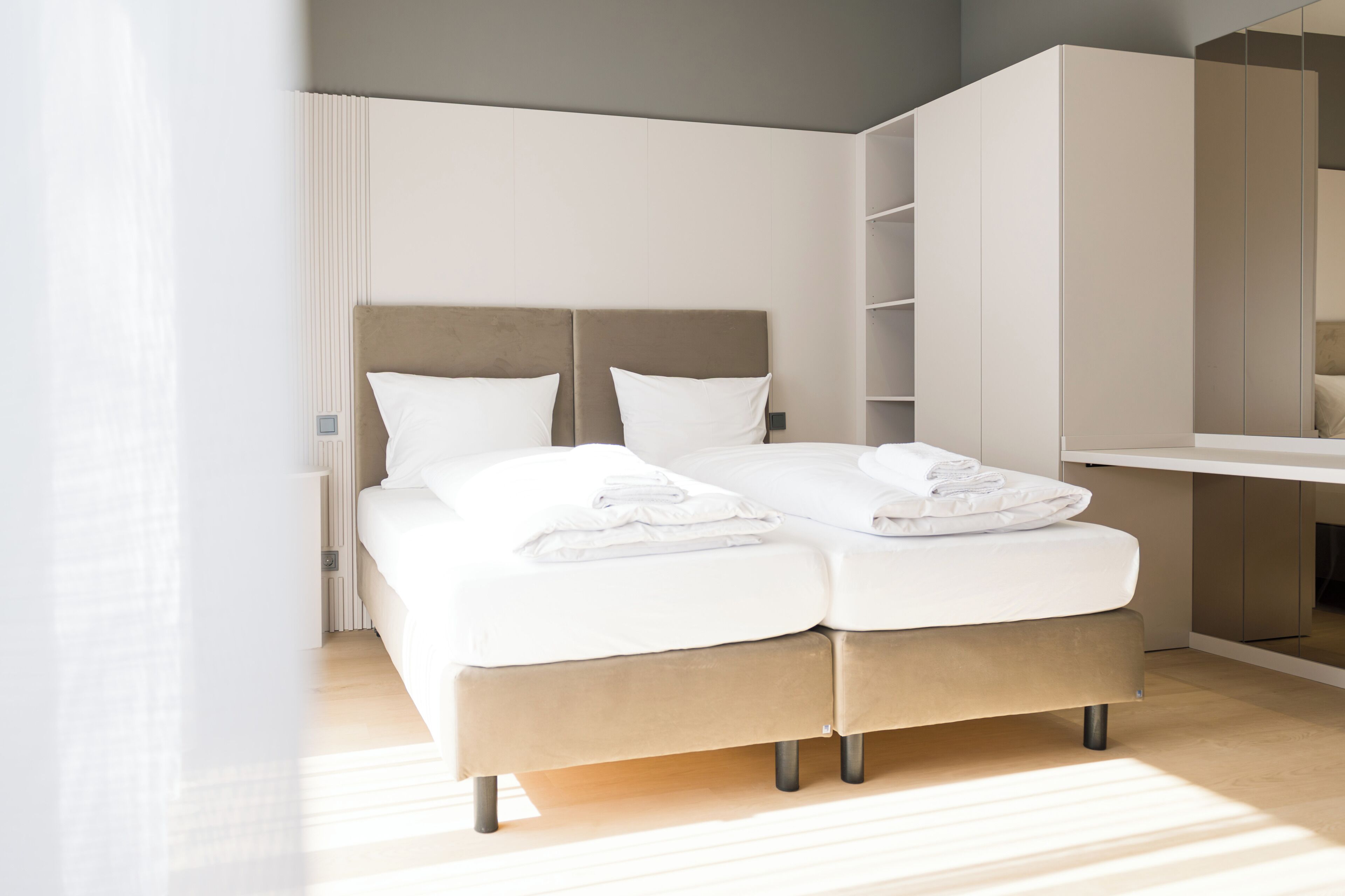A modern bedroom with a bed, a wardrobe, and a mirror.