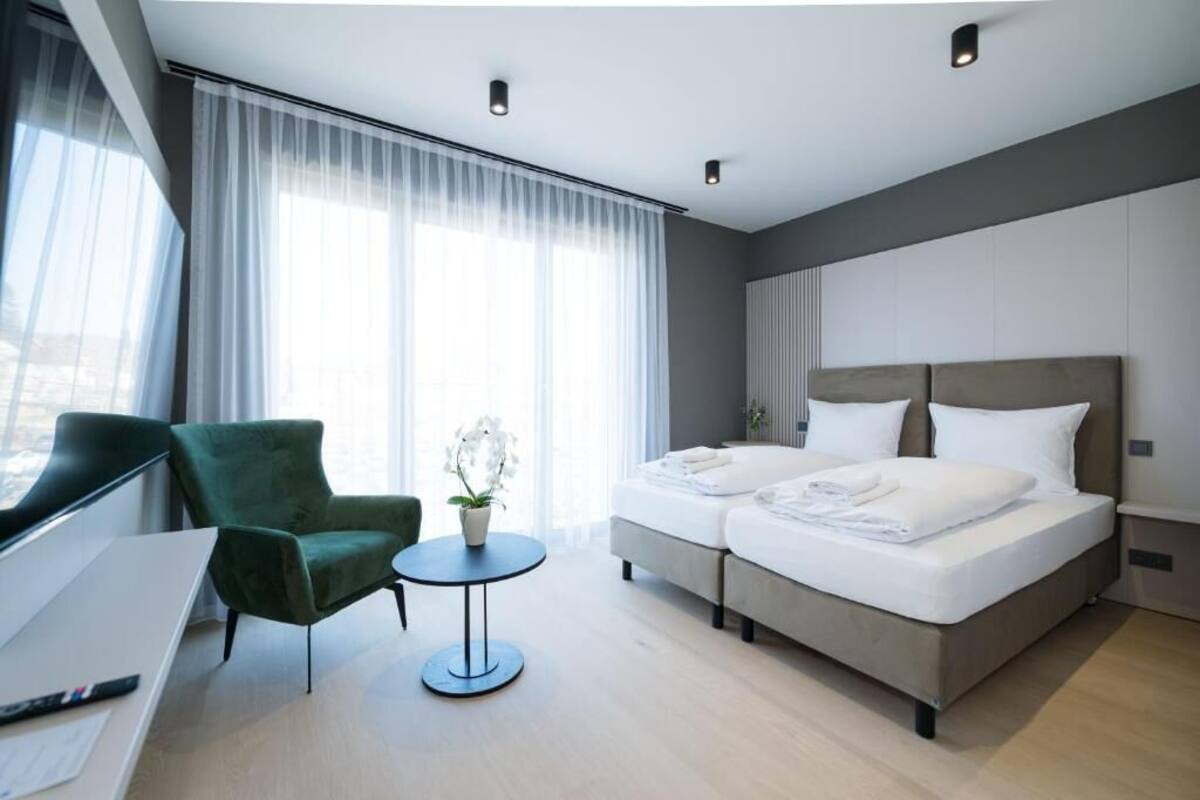 A hotel room with a bed, a desk, a chair, and a small table.