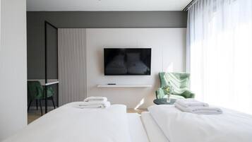 Una moderna camera d'albergo con un letto, una TV, una scrivania e una sedia.