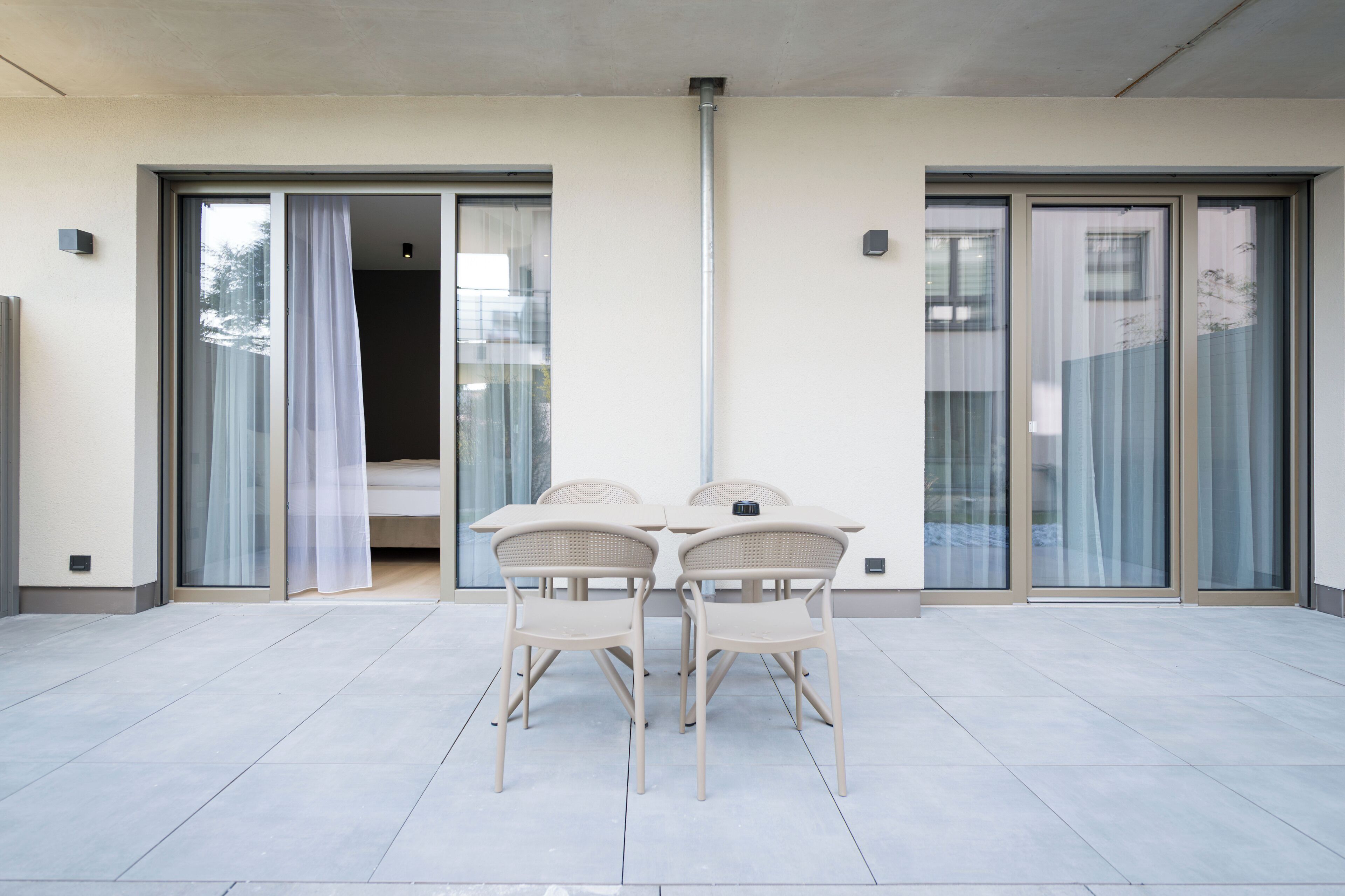 A balcony with a table and chairs, sliding glass doors, and a view of the outside.