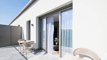 Ein Balkon mit Tisch und Stühlen, einem Blumentopf und einer Glasschiebetür zu einem Innenraum.