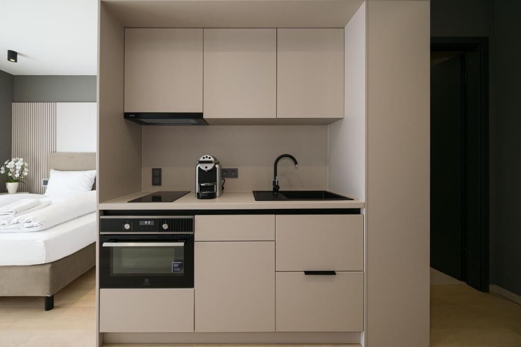 A compact kitchenette with a built-in oven, a coffee maker, and a sink.
