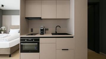 A compact kitchenette with a built-in oven, a coffee maker, and a sink.
