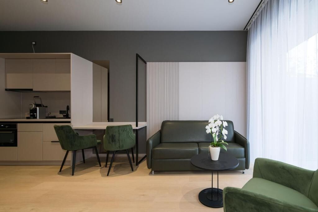 A modern living space with a sofa, a dining table, two chairs, and a potted plant.