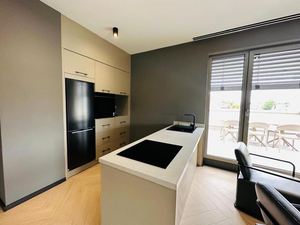 A modern kitchen with a central island, built-in appliances, and a large sliding glass door to a patio area.