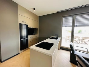 Una cocina moderna con una isla central, electrodomésticos integrados y un amplio ventanal corredera a un patio.