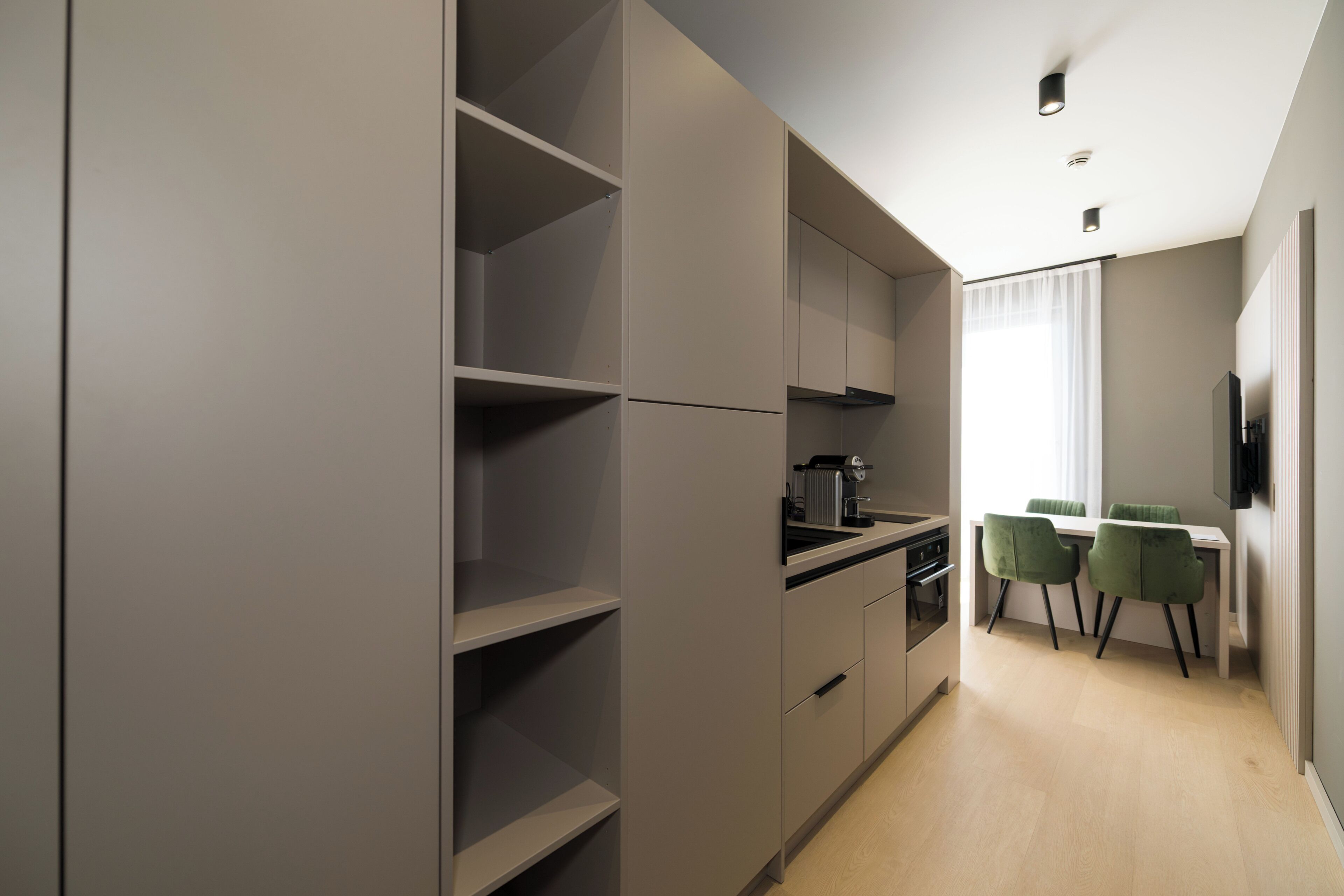 A modern kitchen with built-in appliances, a dining area with a table and chairs, and a large window with curtains.