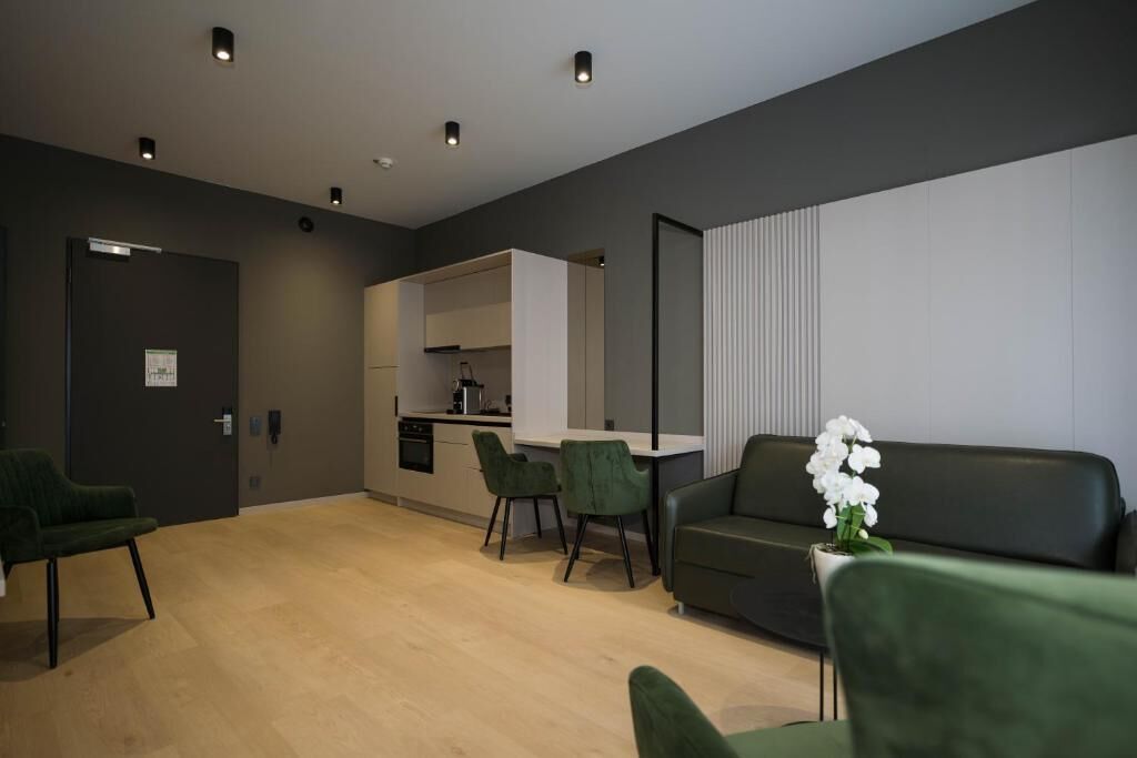 Un espacio habitable moderno con sofá, sillas, una mesa de comedor y una cocina al fondo.