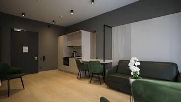 Un espacio habitable moderno con sofá, sillas, una mesa de comedor y una cocina al fondo.