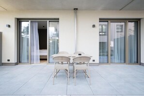 A balcony with a table and chairs, a sliding glass door, and a view of the outside.