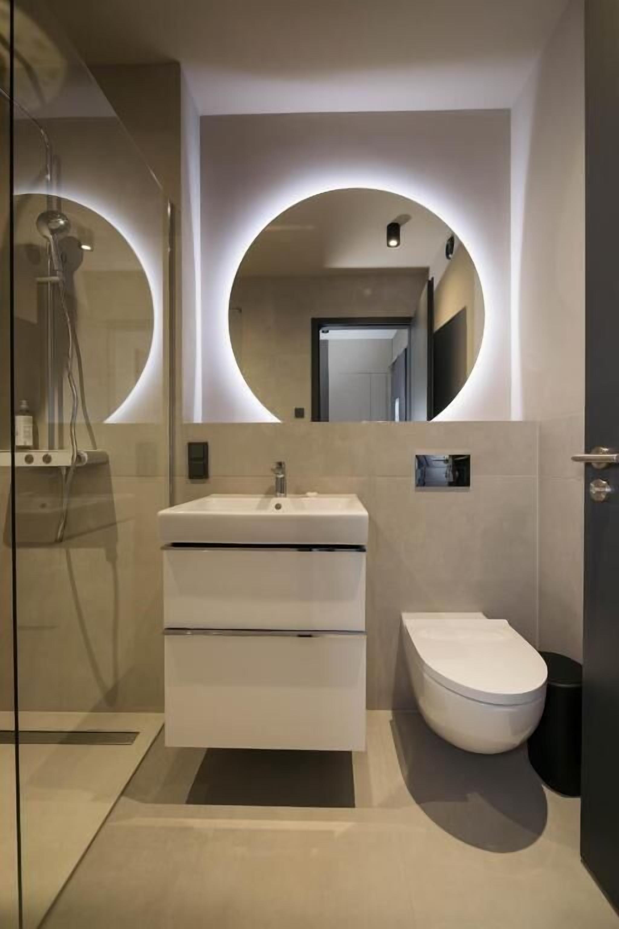 A modern bathroom with a glass shower enclosure, a white sink, and a toilet.